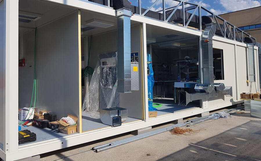 Unità sanitaria modulare prefabbricata in fase di allestimento, con impianti di ventilazione e attrezzature interne